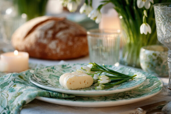Frühlingshafte Tischdeko mit einem Brot im Hintergrund auf dem Tisch.